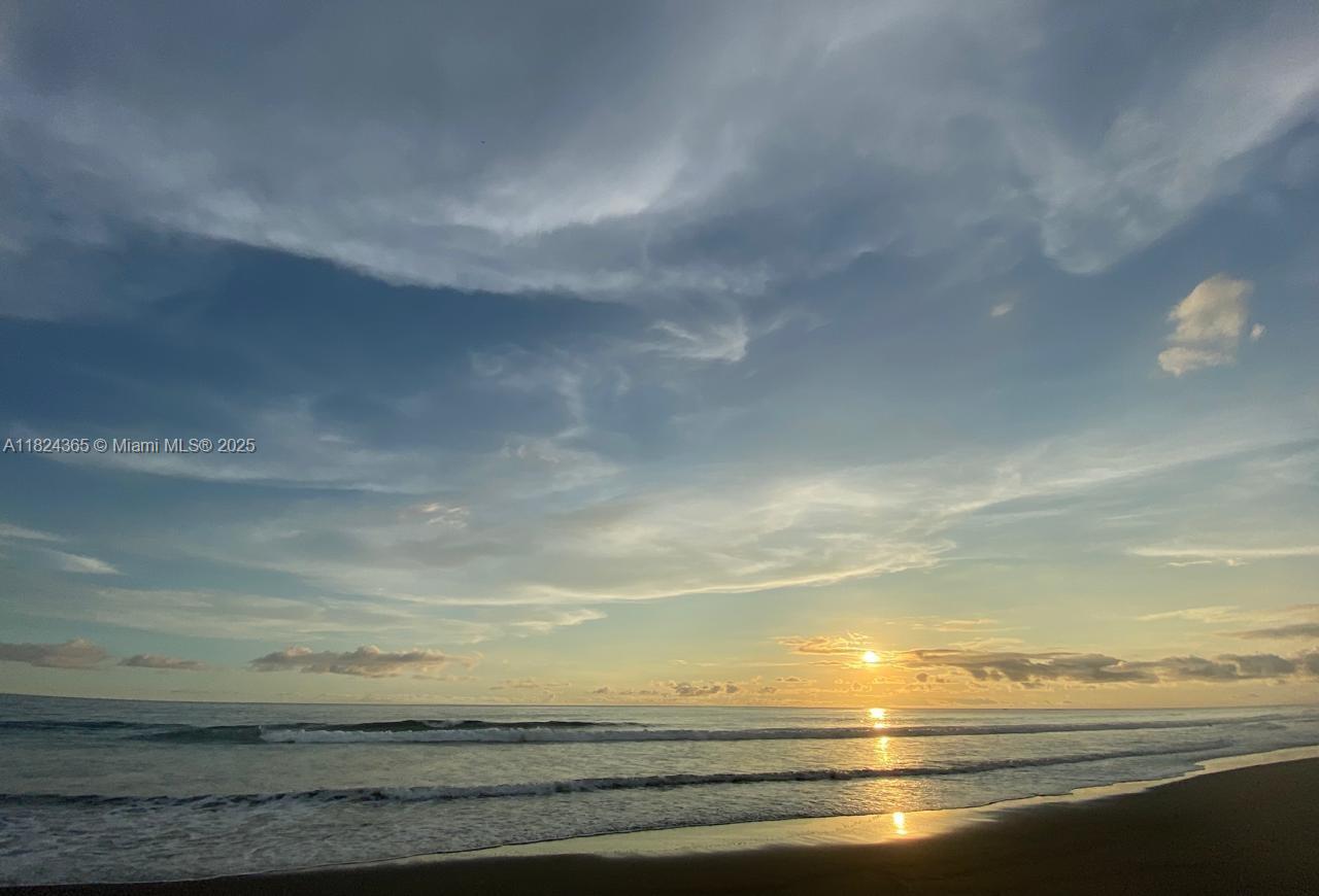 A view of the ocean and beach at sunrise under a cloudy sky — 27 de Abril Playa Junquillal, IA 50303, IA