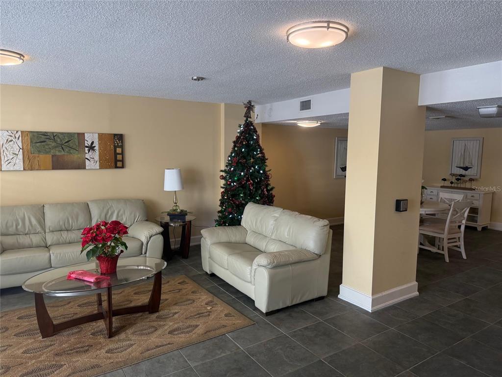 A living room features light-colored leather sofas, a Christmas tree, and tile flooring — 925 N HALIFAX AVENUE UNIT 102, DAYTONA BEACH, FL