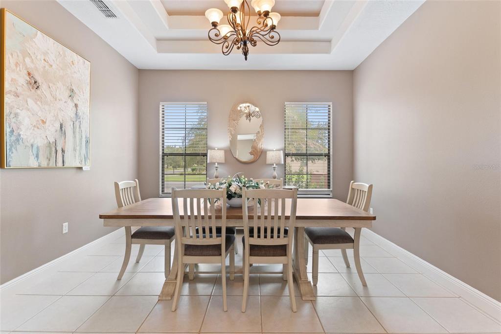 A dining room features a wooden table, six chairs, a chandelier, and a tray ceiling — 915 SAN RAPHAEL STREET, POINCIANA, FL