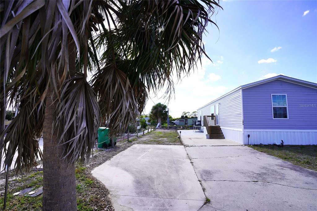 A light purple manufactured home features a concrete driveway and a palm tree in front — 1276 SEAGULL DRIVE, ENGLEWOOD, FL