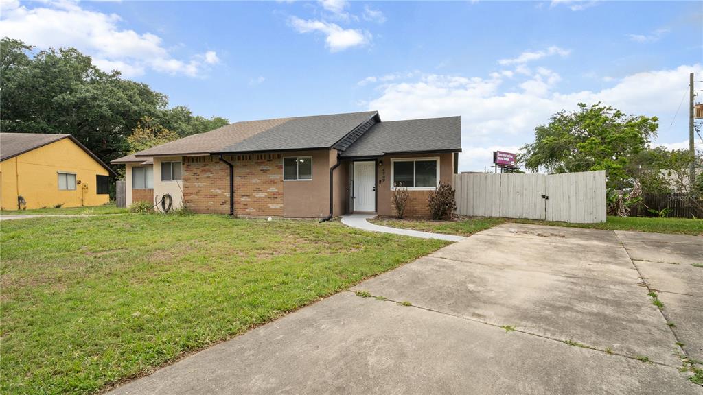 A single-story duplex with a brick and stucco exterior, a white front door, and a driveway — 4999 DOVER CIRCLE, ORLANDO, FL