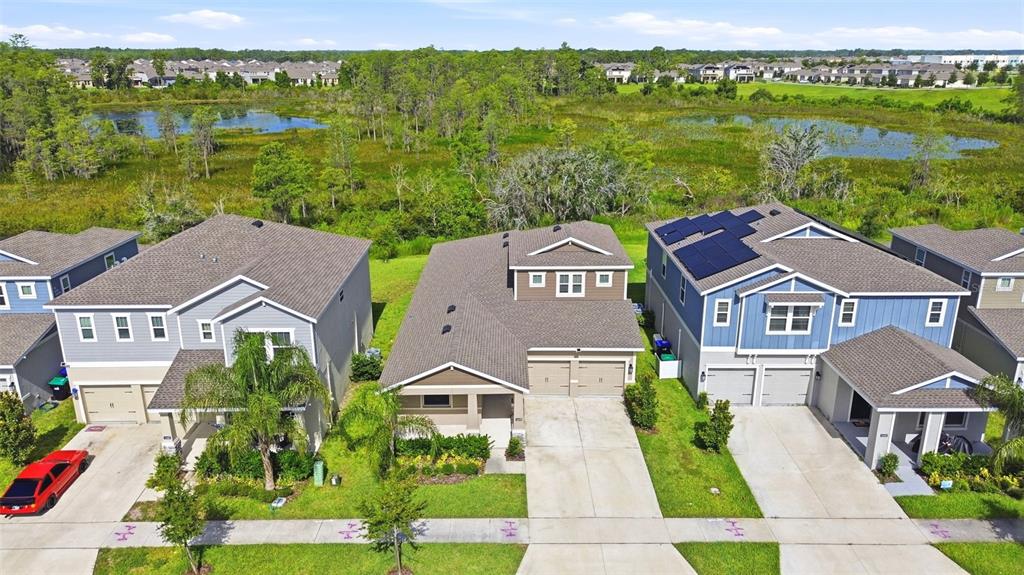 An aerial view shows three suburban houses with driveways facing a grassy wetland area — 16448 PARABLE WAY, WINTER GARDEN, FL