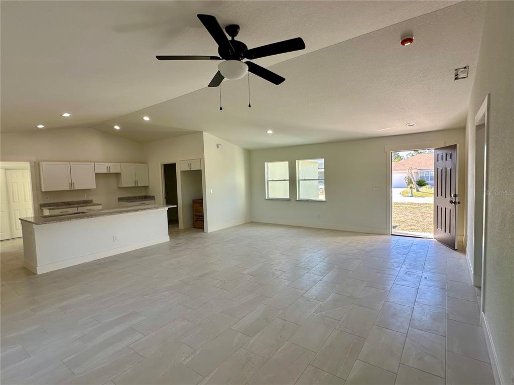 An open-concept living area features a kitchen with white cabinets, tile flooring, and a ceiling fan — 9172 RAVEL STREET, PORT CHARLOTTE, FL