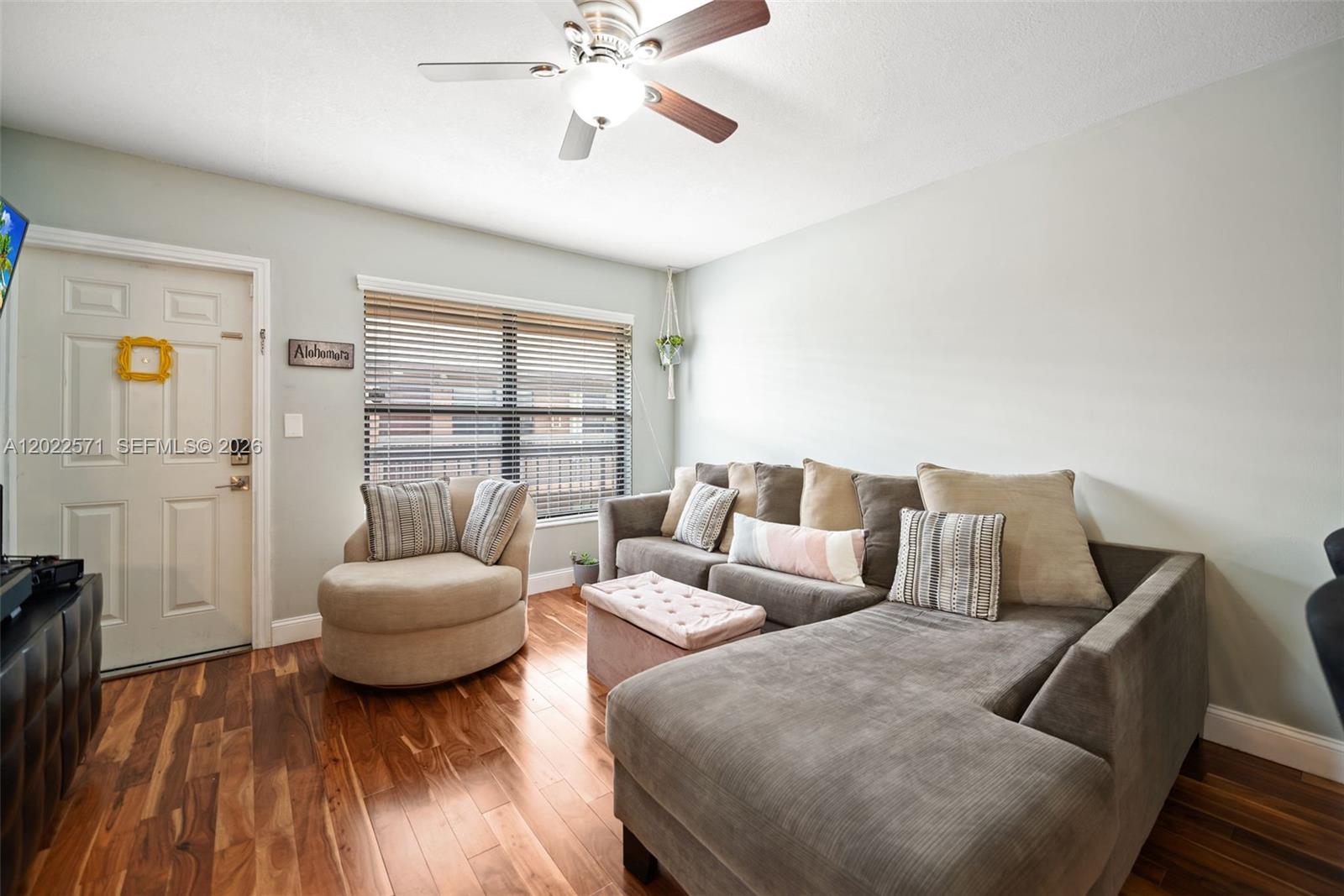 A living room features a sectional sofa, a round chair, and wood flooring — 10049 Winding Lake Rd # 202, Sunrise FL 33351, SUNRISE, FL