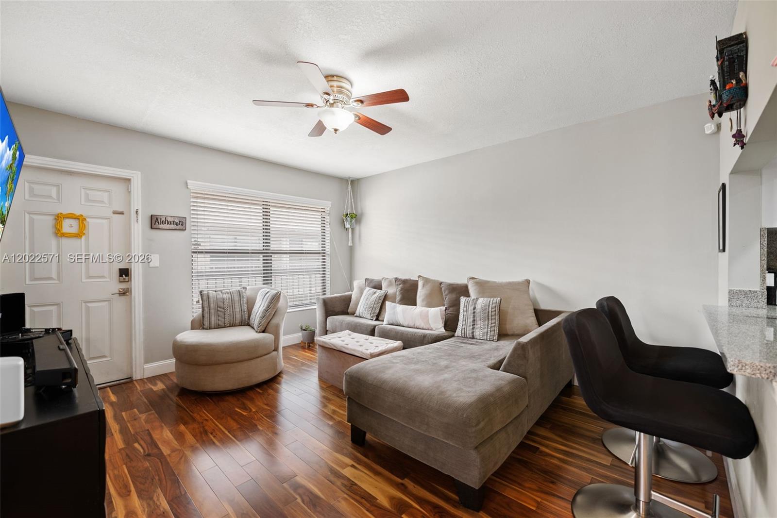 A living room features a sectional sofa, a round chair, and dark wood flooring — 10049 Winding Lake Rd # 202, Sunrise FL 33351, SUNRISE, FL