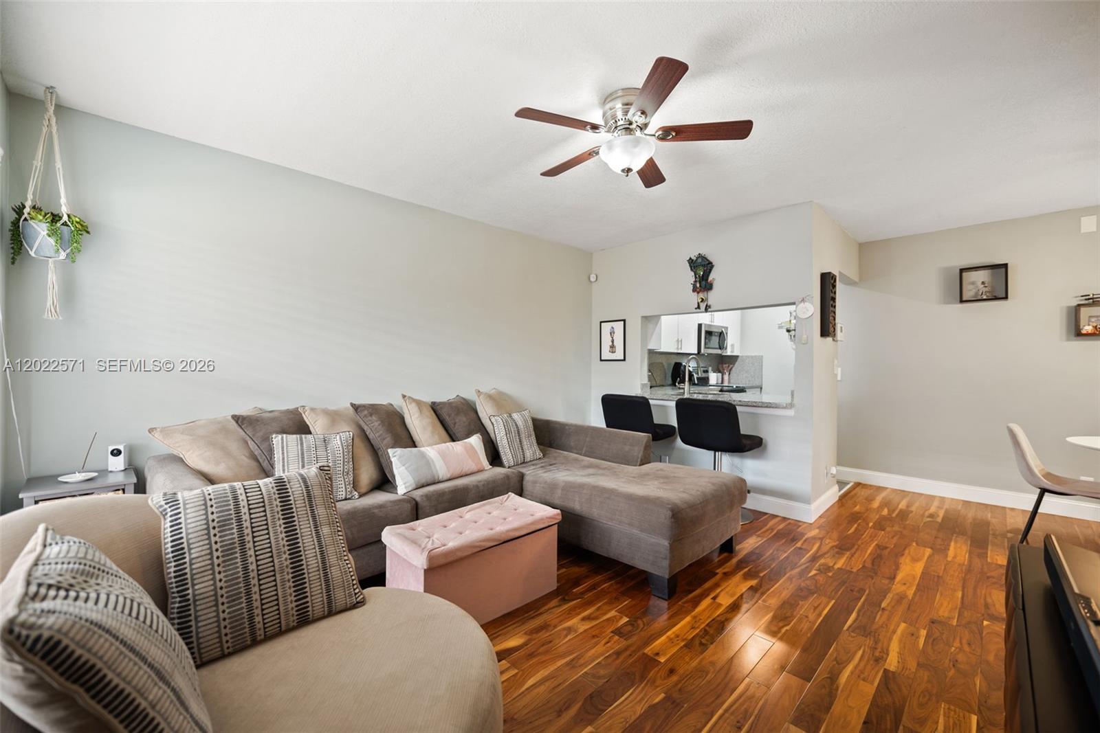 A living room features a sectional sofa, hardwood floors, and a pass-through to the kitchen — 10049 Winding Lake Rd # 202, Sunrise FL 33351, SUNRISE, FL
