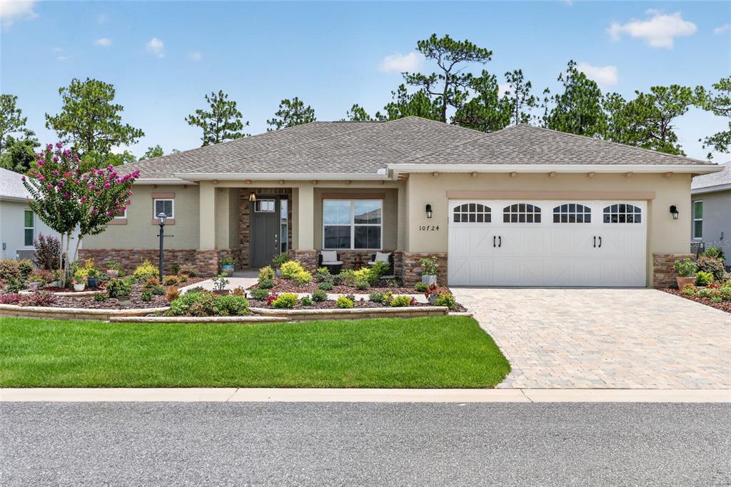 A single-story house with a stone-accented facade, a two-car garage, and a landscaped front yard — 10724 SW 101ST LOOP, OCALA, FL