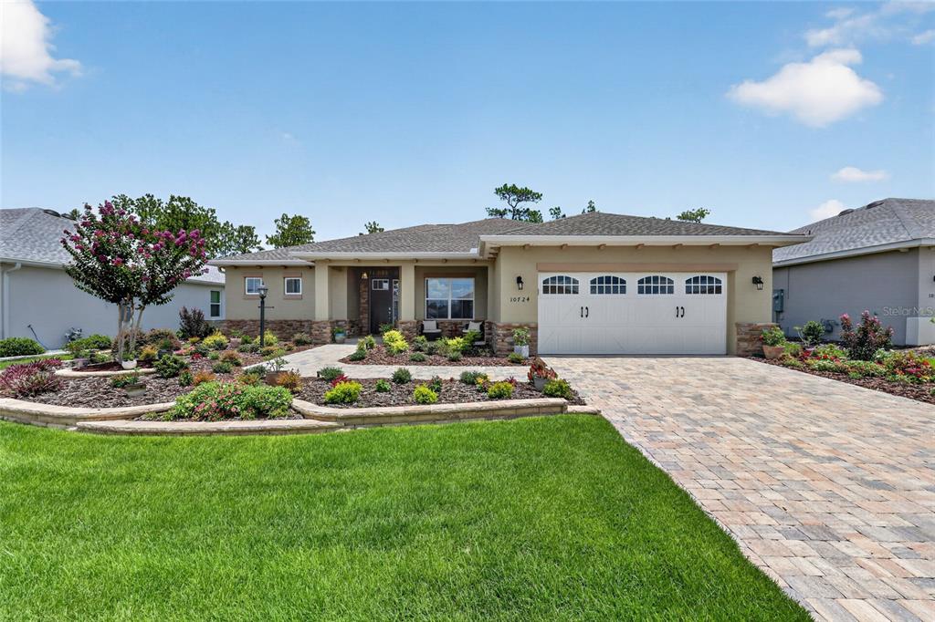 A single-story house with a stone-accented facade, a two-car garage, and a landscaped front yard — 10724 SW 101ST LOOP, OCALA, FL