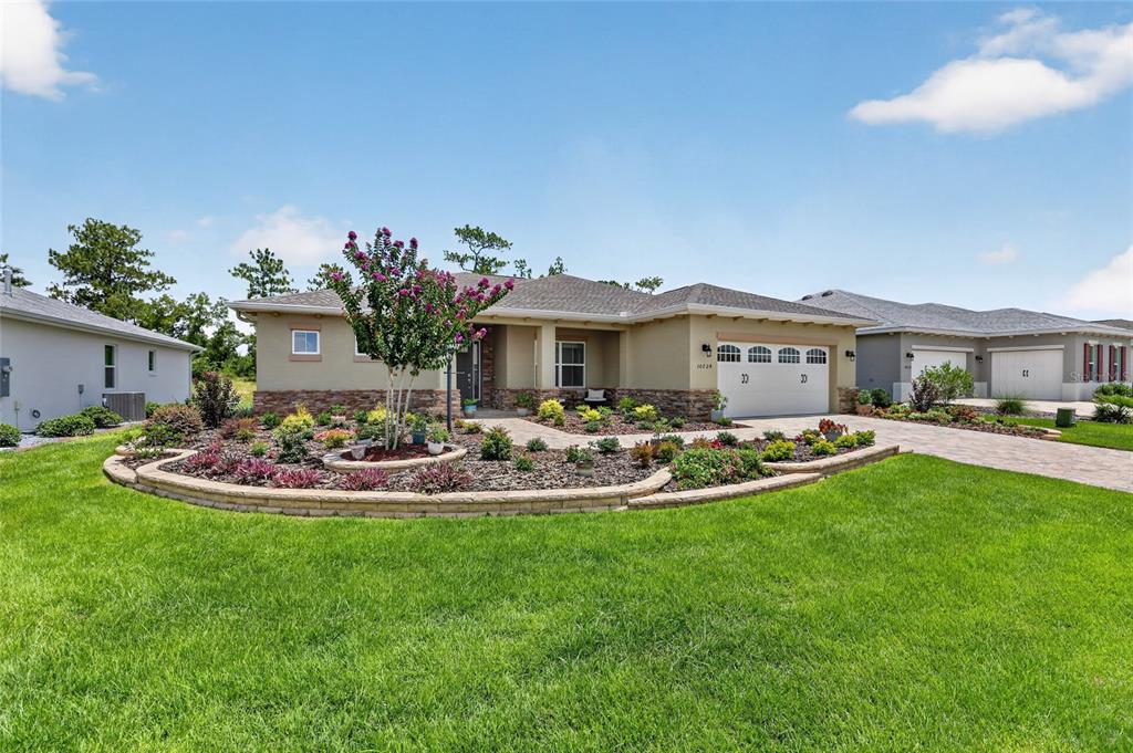 A view of a grassy backyard with a garden bed and trees under a blue sky — 10724 SW 101ST LOOP, OCALA, FL