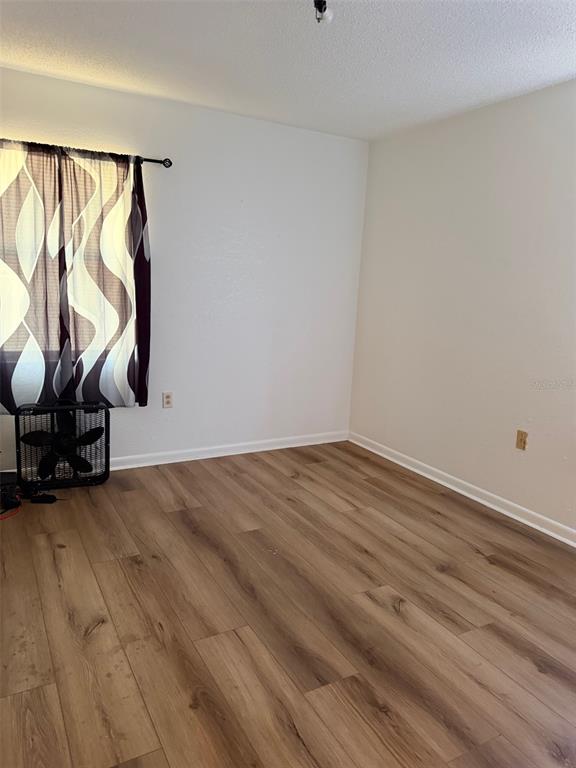 An empty bedroom features white walls, light wood-look flooring, and a window with patterned curtains — 205 NE 147 STREET, CROSS CITY, FL