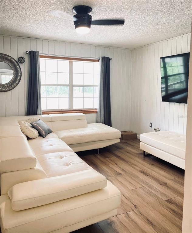 A living room features white paneled walls, a white sectional sofa, and wood-look flooring — 205 NE 147 STREET, CROSS CITY, FL
