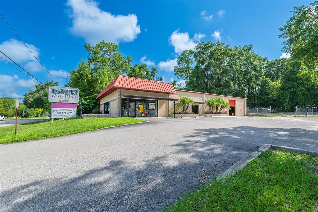 A commercial building with a red metal roof and a parking lot in front — 305 SW 250TH STREET, NEWBERRY, FL