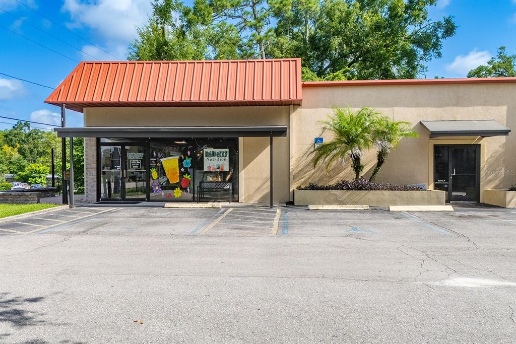 An exterior view of a commercial building with a red metal roof and parking lot — 305 SW 250TH STREET, NEWBERRY, FL