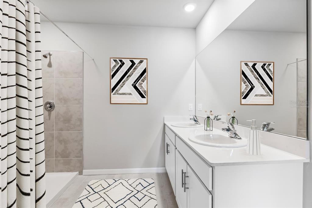 A modern bathroom features a double vanity, a large mirror, and a tiled walk-in shower — 26233 CORAL LAKES DRIVE, PUNTA GORDA, FL