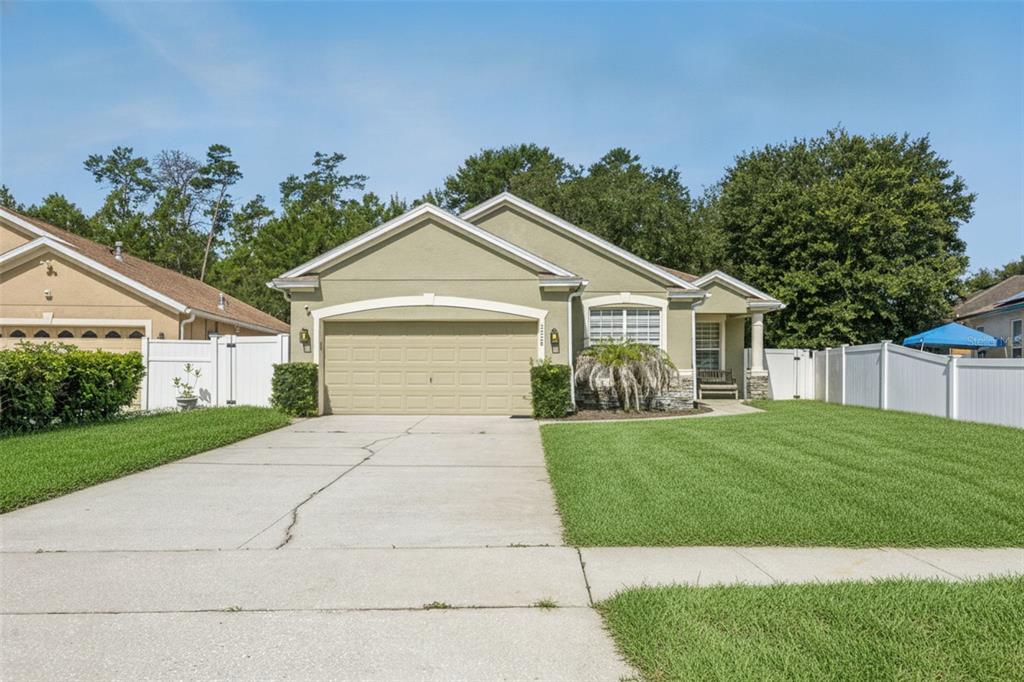 A single-story house with a green stucco exterior, a two-car garage, and a front lawn — 3528 BERKSHIRE WOODS TERRACE, DELTONA, FL