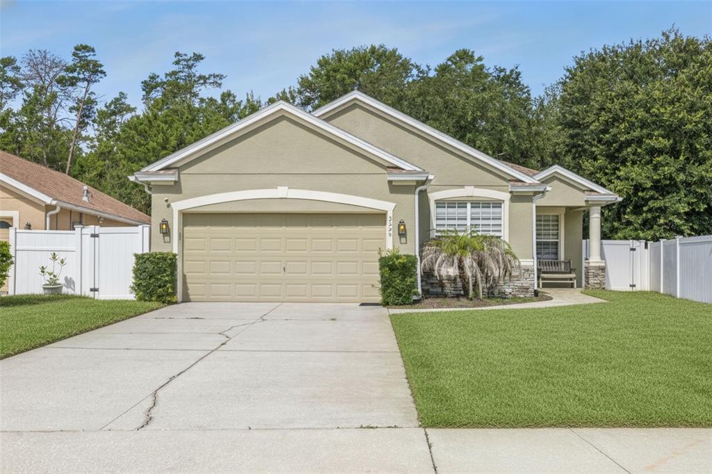 A single-story house with a tan stucco exterior, stone accents, and a paved walkway — 3528 BERKSHIRE WOODS TERRACE, DELTONA, FL