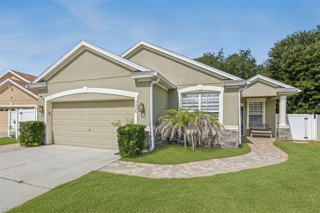 A single-story house exterior features a stone-accented facade, a paver walkway, and a palm tree — 3528 BERKSHIRE WOODS TERRACE, DELTONA, FL
