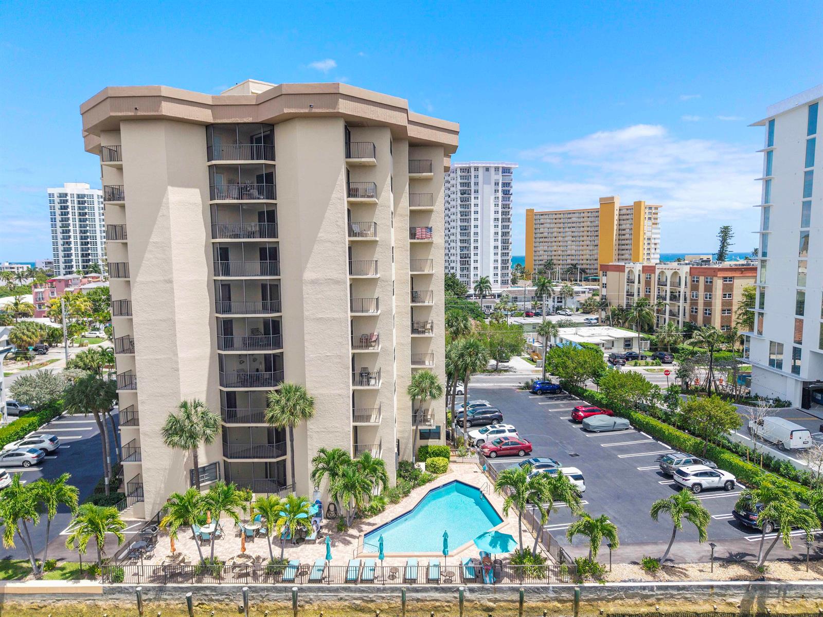 An aerial view shows a tan high-rise condominium building with a pool and parking lot — 501 N Riverside Drive # 203, Pompano Beach FL 33062, POMPANO BEACH, FL