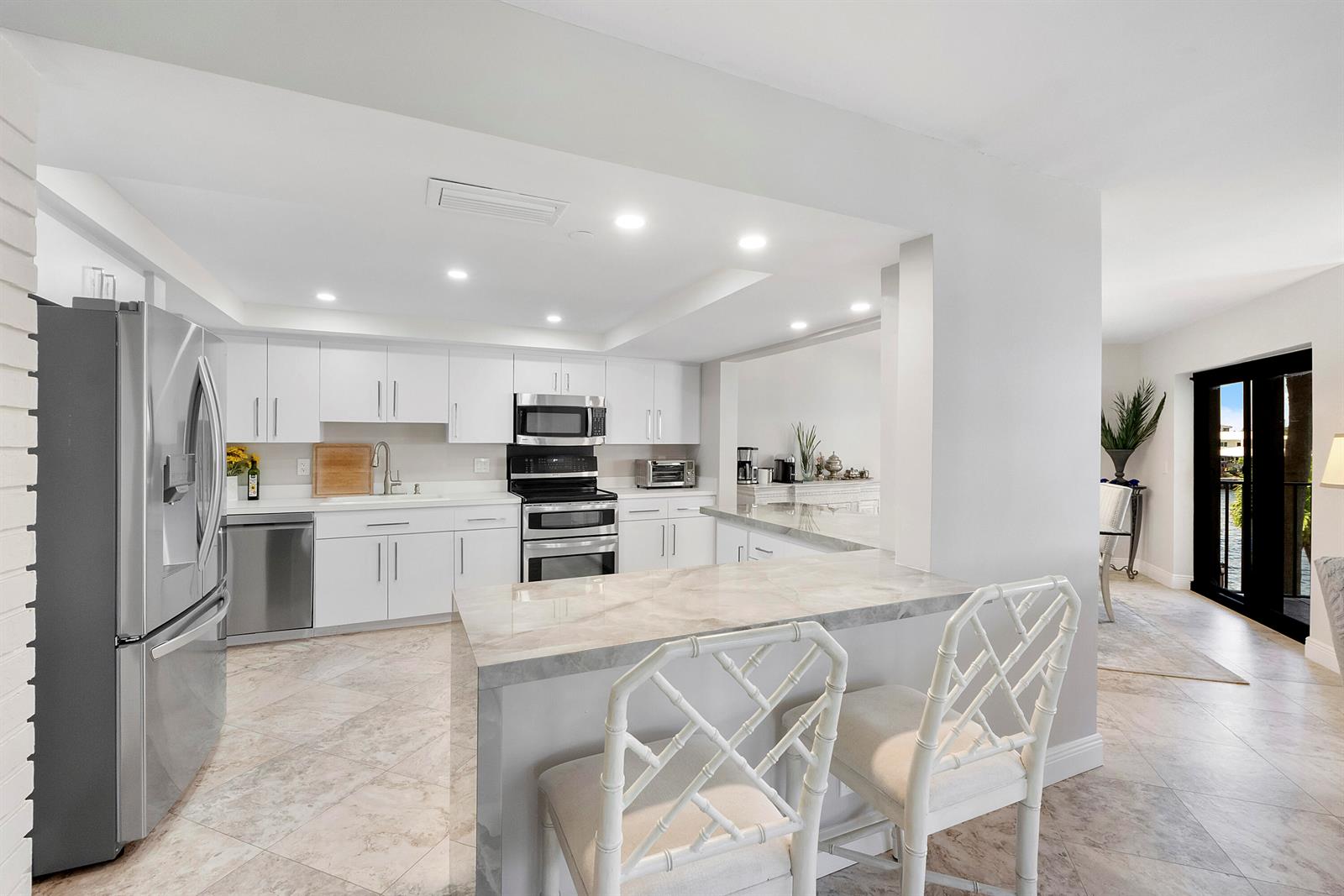A modern kitchen features white cabinetry, stainless steel appliances, and a marble-topped breakfast bar — 501 N Riverside Drive # 203, Pompano Beach FL 33062, POMPANO BEACH, FL