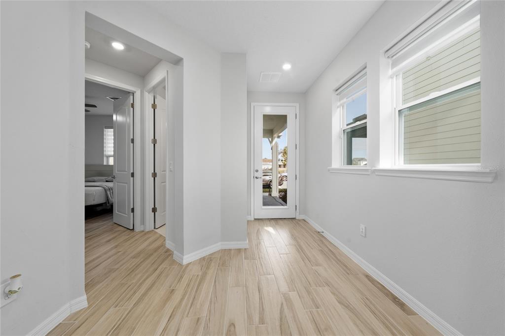 A bright hallway with light wood-look tile flooring leads to an exterior glass door — 6430 ROVER WAY, ST CLOUD, FL