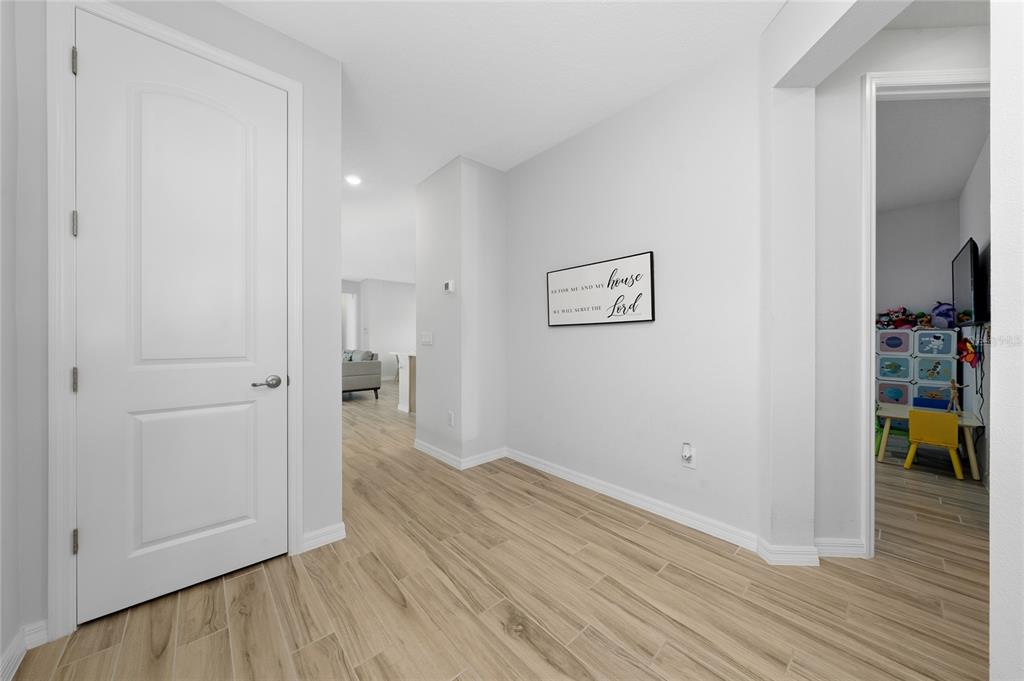 A hallway with light wood-look flooring, a white door, and a wall sign — 6430 ROVER WAY, ST CLOUD, FL