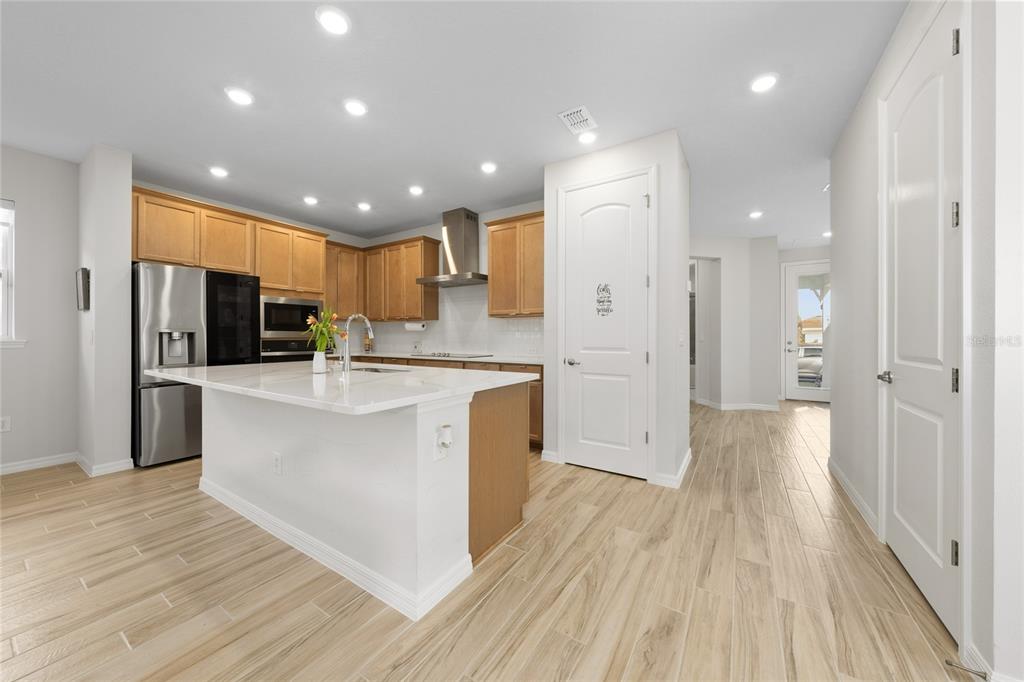 A modern kitchen features light wood cabinets, a white quartz island, and wood-look tile flooring — 6430 ROVER WAY, ST CLOUD, FL