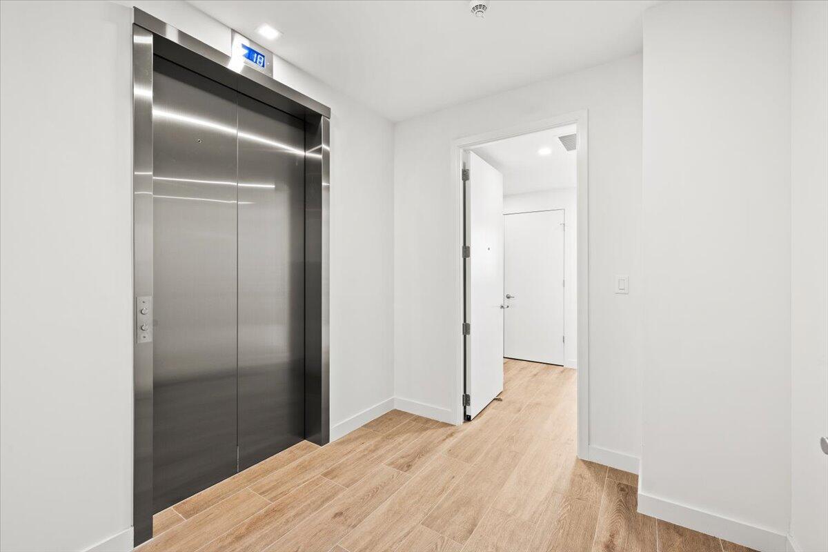 A hallway features light wood-look flooring, a stainless steel elevator, and an open doorway — 900 N Ocean Boulevard # 305, Pompano Beach FL 33062, POMPANO BEACH, FL