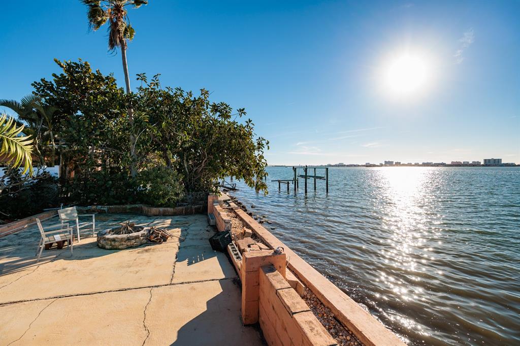 A concrete patio with a fire pit overlooks a bay with a distant city skyline — 1844 VENETIAN POINT DRIVE, CLEARWATER, FL