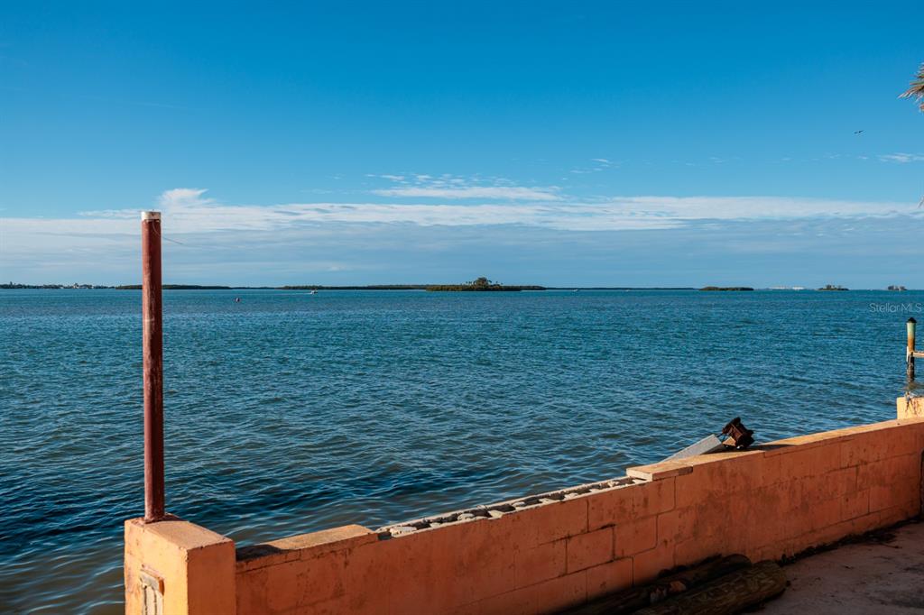 A view of a body of water from behind a low, orange concrete block wall — 1844 VENETIAN POINT DRIVE, CLEARWATER, FL