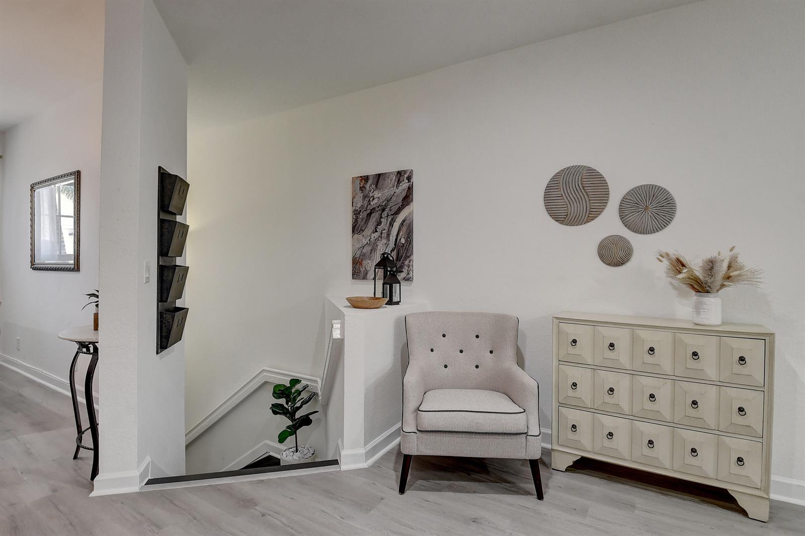 A light-filled entryway features a tufted armchair, a chest of drawers, and a staircase — 525 Bayfront Drive, Boynton Beach FL 33435, BOYNTON BEACH, FL