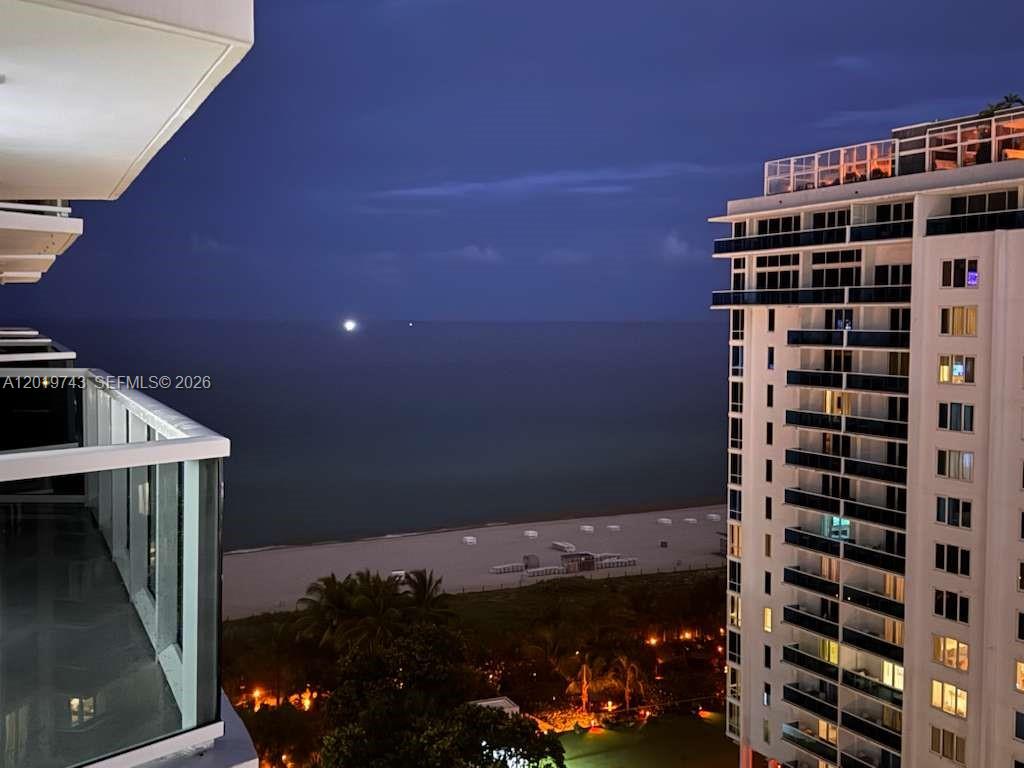 A balcony view overlooks a sandy beach and the ocean at twilight — 2401 Collins Ave # 1807, Miami Beach FL 33140, MIAMI BEACH, FL