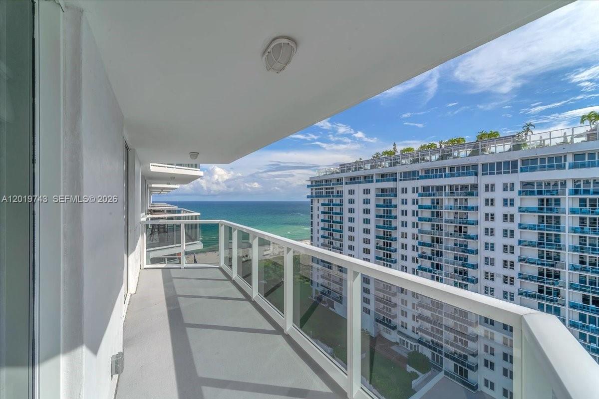 A high-rise balcony features a glass railing overlooking the ocean and a neighboring building — 2401 Collins Ave # 1807, Miami Beach FL 33140, MIAMI BEACH, FL