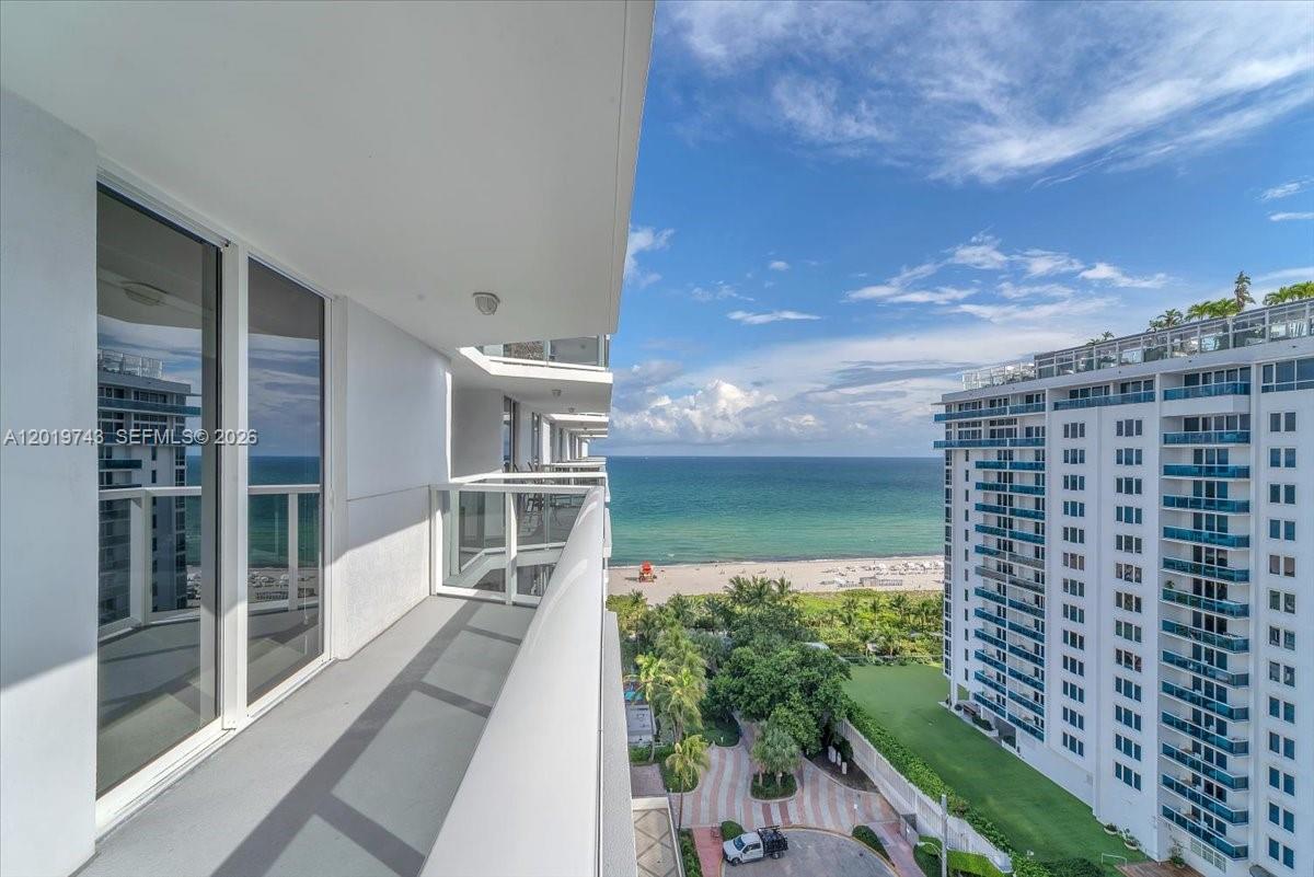 A high-rise balcony overlooks a sandy beach, the ocean, and a neighboring apartment building — 2401 Collins Ave # 1807, Miami Beach FL 33140, MIAMI BEACH, FL