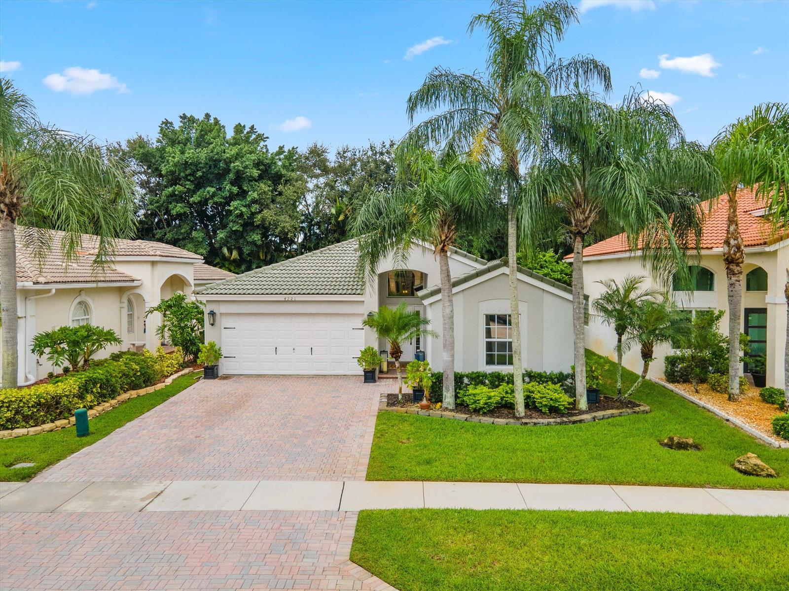 A single-story house with a paved driveway, a two-car garage, and palm trees in front — 4221 Bluff Harbor Way, Wellington FL 33449, WELLINGTON, FL