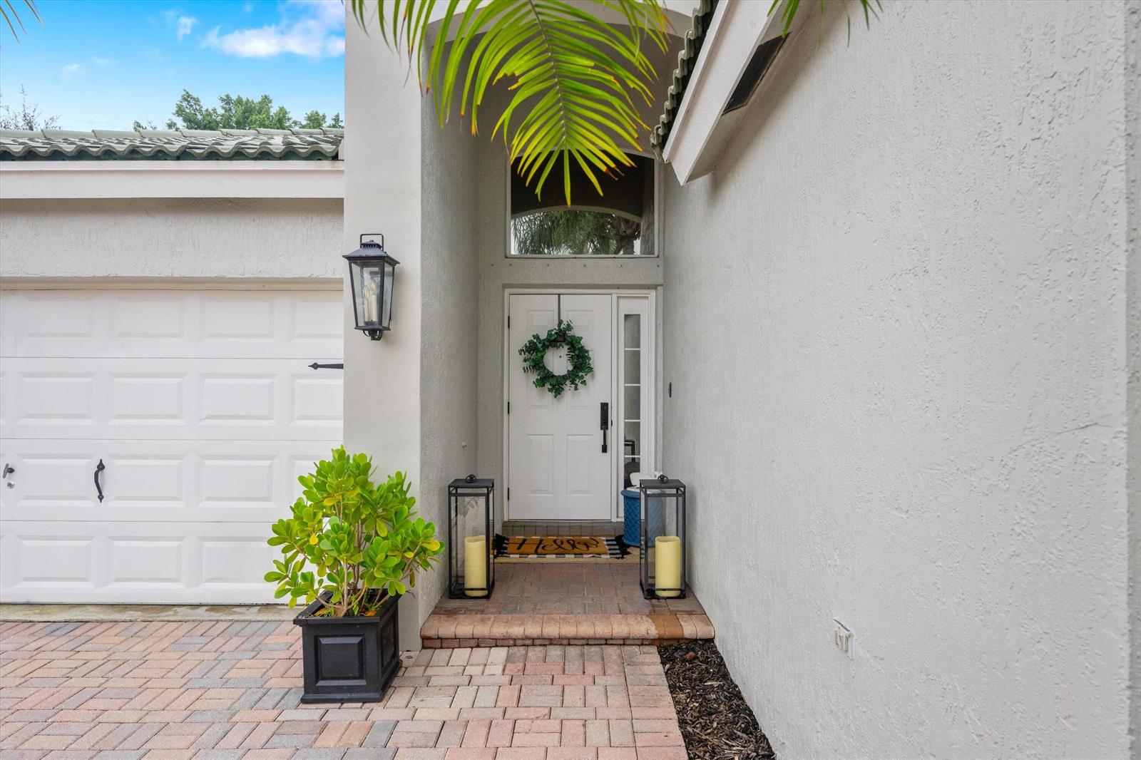 The exterior of a home features a white front door, a brick walkway, and a garage — 4221 Bluff Harbor Way, Wellington FL 33449, WELLINGTON, FL