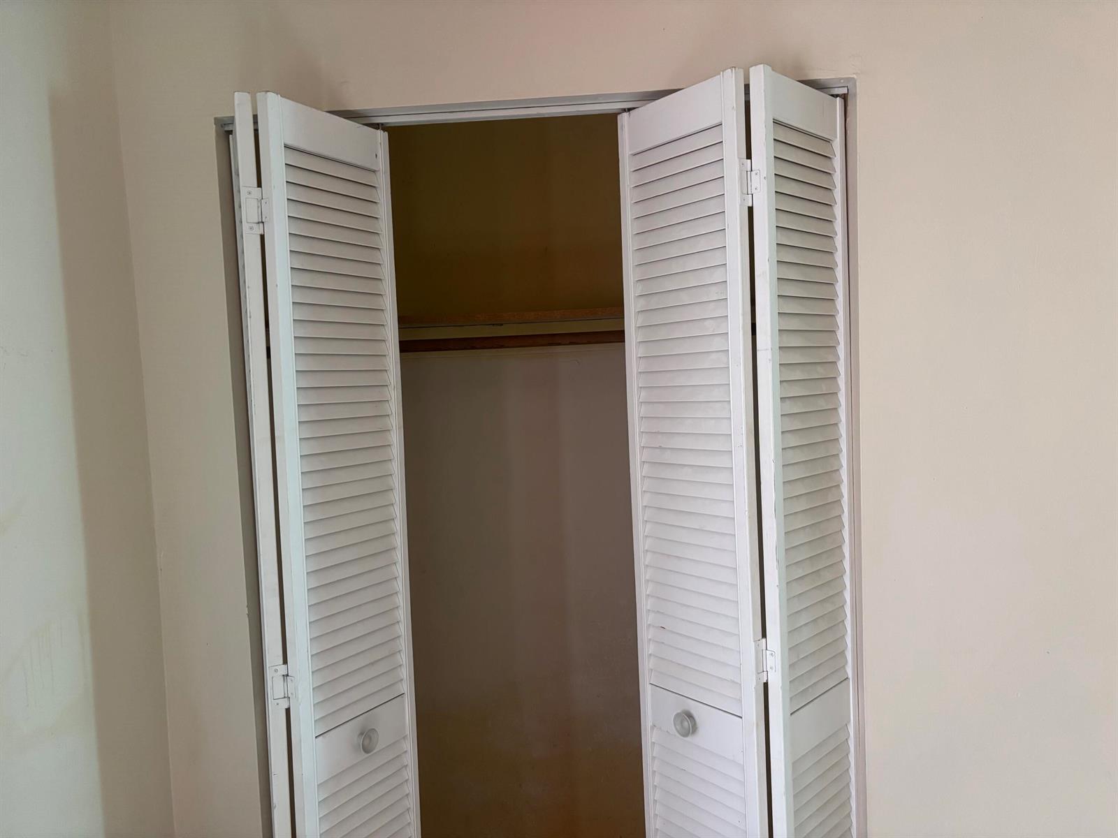 A white louvered bifold closet door stands partially open in a room with beige walls — 1250 SW 5TH Terrace, Deerfield Beach FL 33441, DEERFIELD BEACH, FL