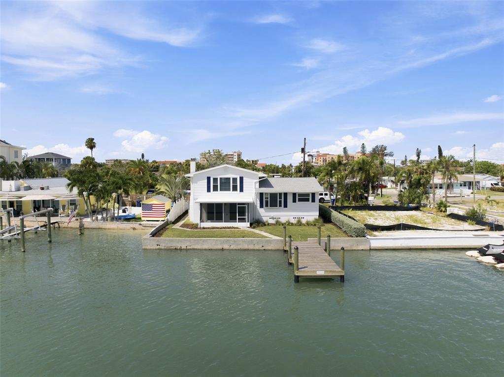 A white two-story house sits on a waterfront lot with a private wooden dock — 13155 BOCA CIEGA AVENUE, MADEIRA BEACH, FL