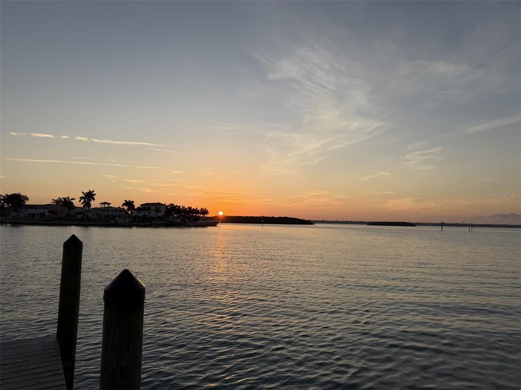 A sunset view over the water from a wooden dock with two pilings — 13155 BOCA CIEGA AVENUE, MADEIRA BEACH, FL