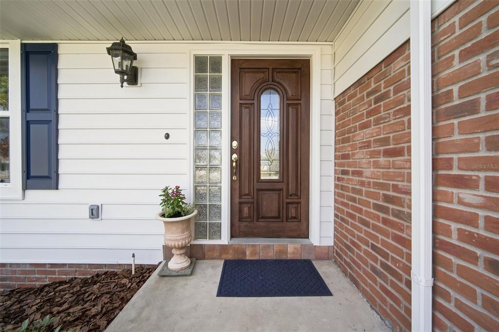 A front porch features a brown wooden door with a glass insert and glass block sidelight — 13155 BOCA CIEGA AVENUE, MADEIRA BEACH, FL