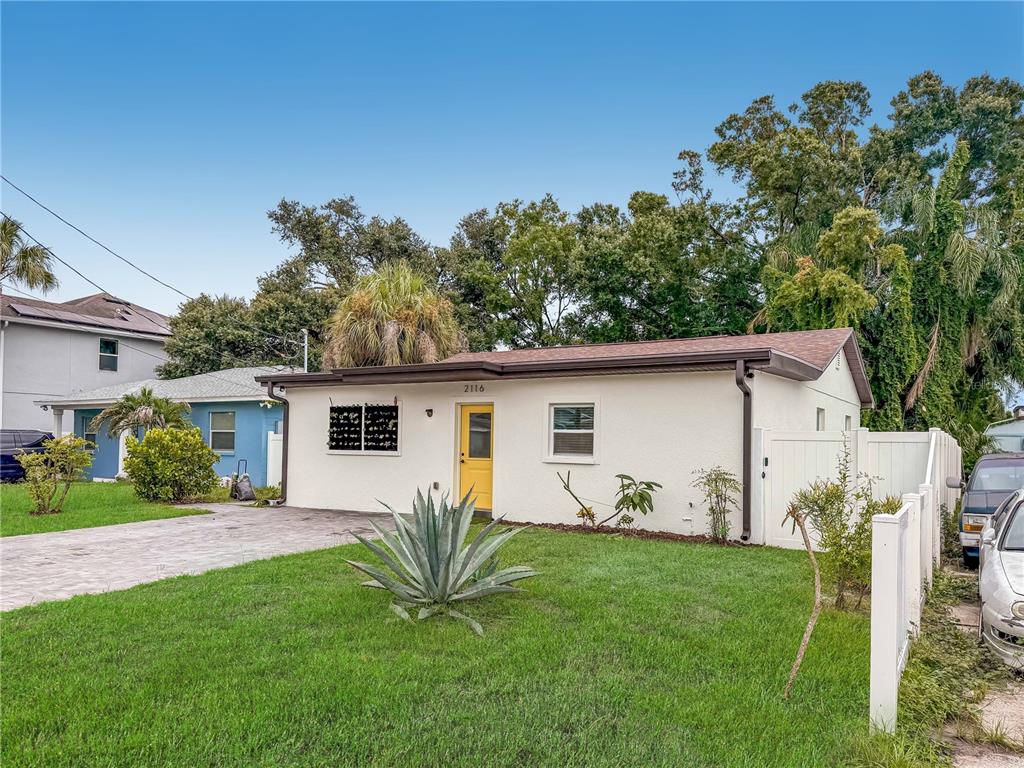 A single-story white house with a yellow front door and a paved driveway — 2116 W STATE STREET, TAMPA, FL