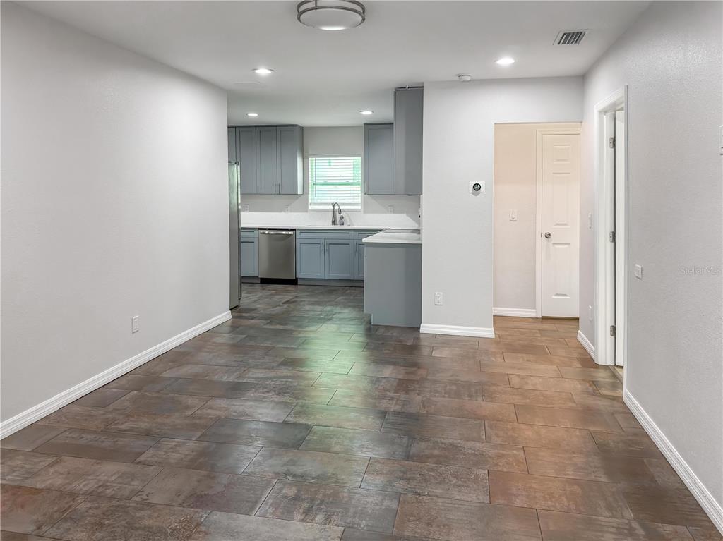 A kitchen with gray cabinets and stainless steel appliances opens to a tiled dining area — 2116 W STATE STREET, TAMPA, FL