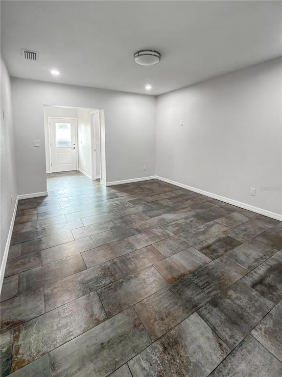 An empty room features gray walls, a flush-mount ceiling light, and large, mottled-gray floor tiles — 2116 W STATE STREET, TAMPA, FL