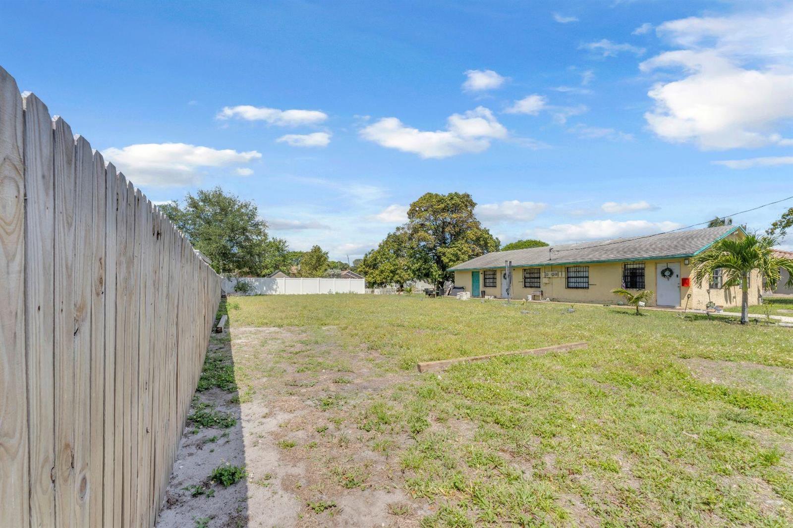A large, grassy backyard features a wooden fence along the left side of the property — 625 NW 15th Avenue, Pompano Beach FL 33069, POMPANO BEACH, FL