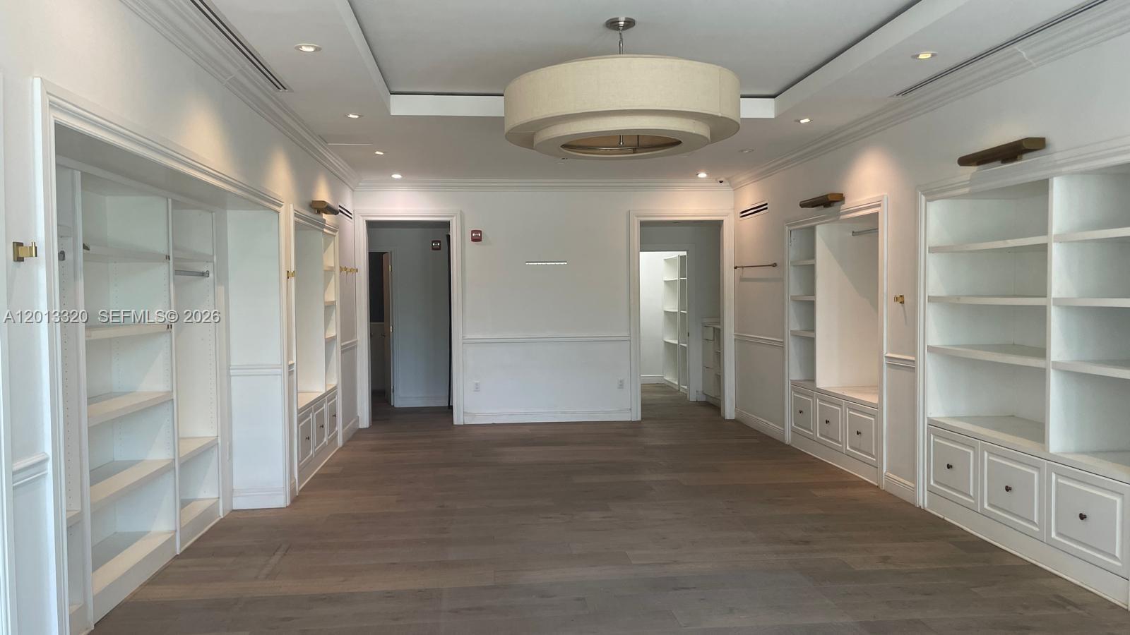 A spacious walk-in closet features white built-in shelving, cabinetry, and light wood flooring — 1201 20th St # 7, Miami Beach FL 33139, MIAMI BEACH, FL