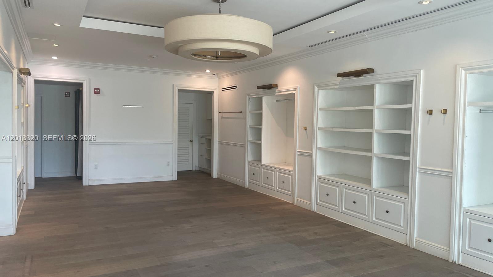 A room with light wood floors, white built-in shelving, and a large circular pendant light — 1201 20th St # 7, Miami Beach FL 33139, MIAMI BEACH, FL