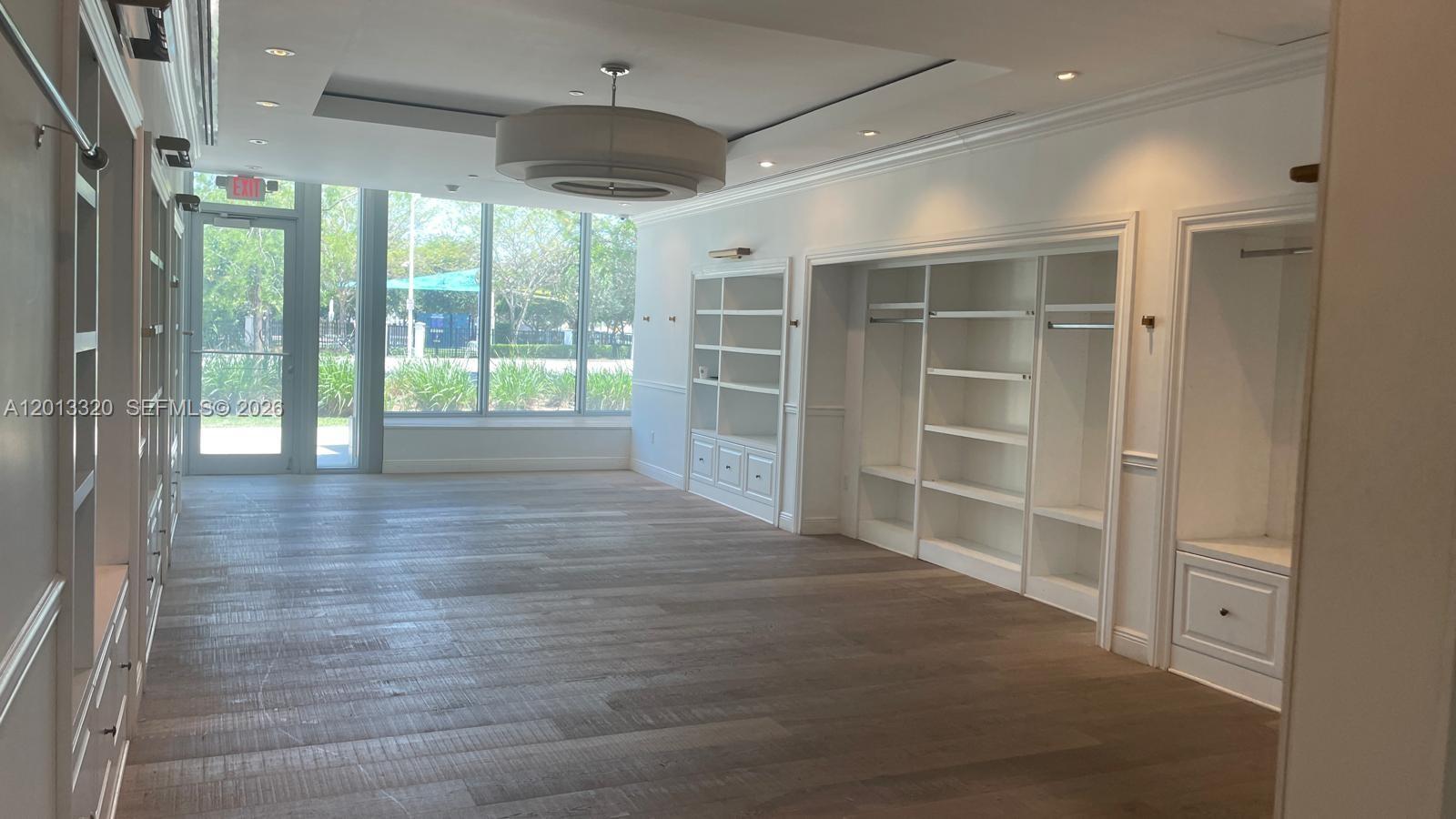 A bright room features light wood floors, built-in white shelving, and large windows with outdoor views — 1201 20th St # 7, Miami Beach FL 33139, MIAMI BEACH, FL