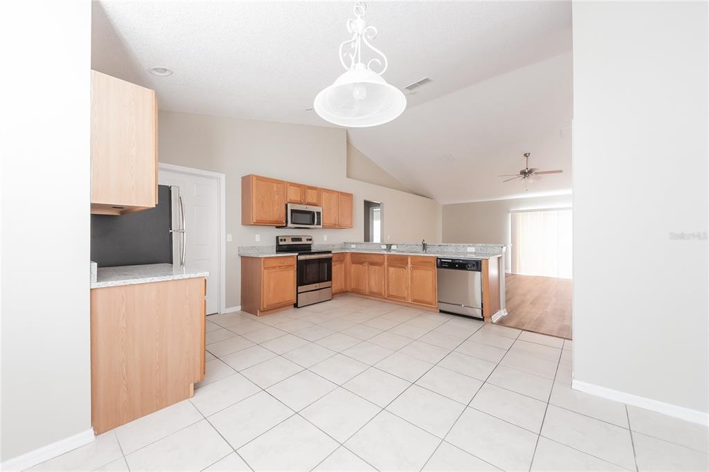 A kitchen with light wood cabinets, stainless steel appliances, and tile flooring — 826 SAN JOSE COURT, KISSIMMEE, FL