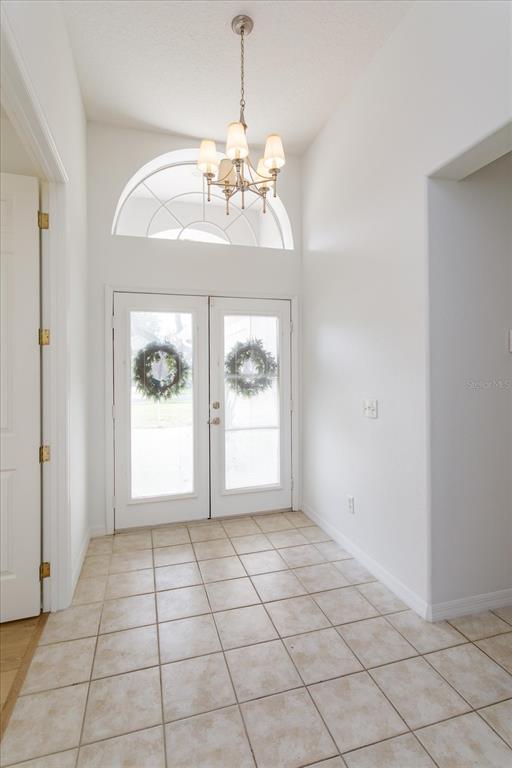 An entryway features a tiled floor, a chandelier, and double glass doors with wreaths — 931 VINDALE ROAD, TAVARES, FL