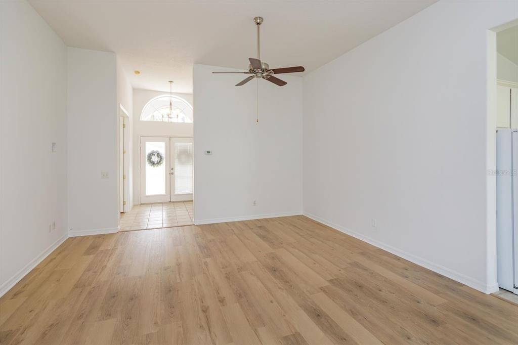 An empty living room features light wood-look flooring, white walls, and a ceiling fan — 931 VINDALE ROAD, TAVARES, FL