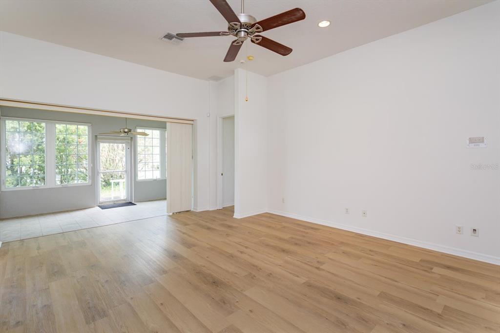 A living room with light wood flooring, white walls, a ceiling fan, and a sunroom — 931 VINDALE ROAD, TAVARES, FL